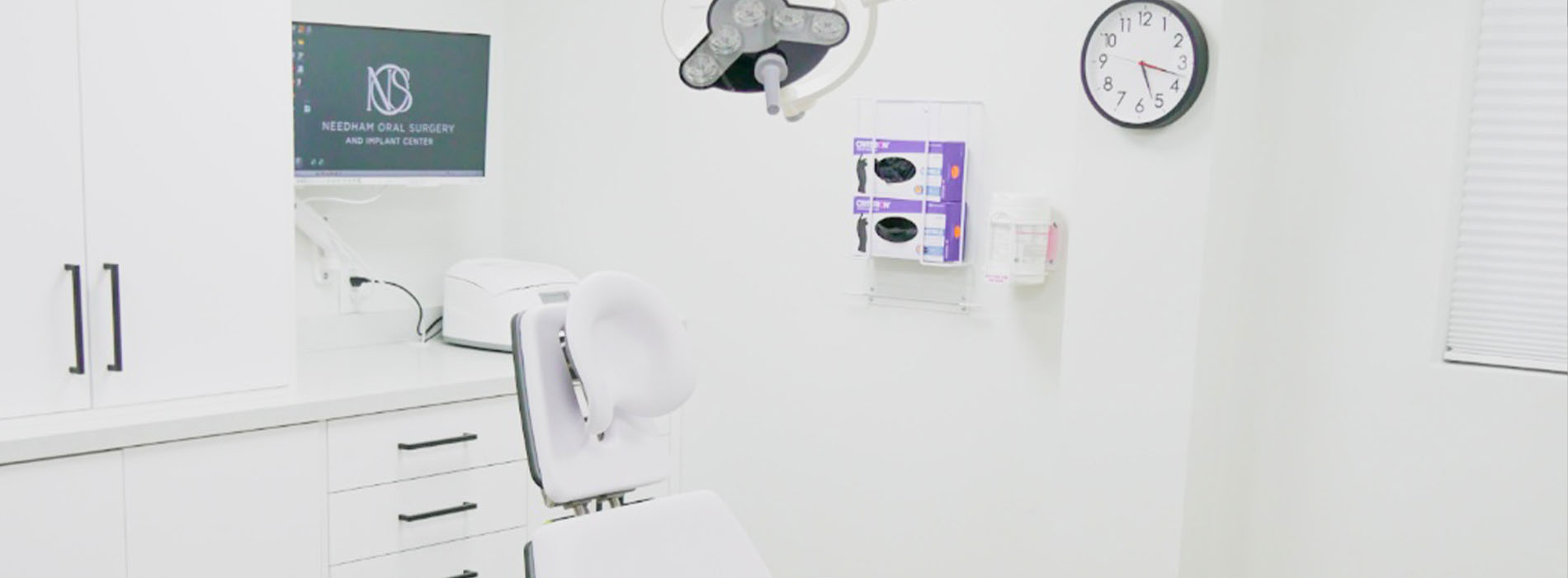 The image shows an interior view of a dental office with various pieces of equipment and a clean, white aesthetic.